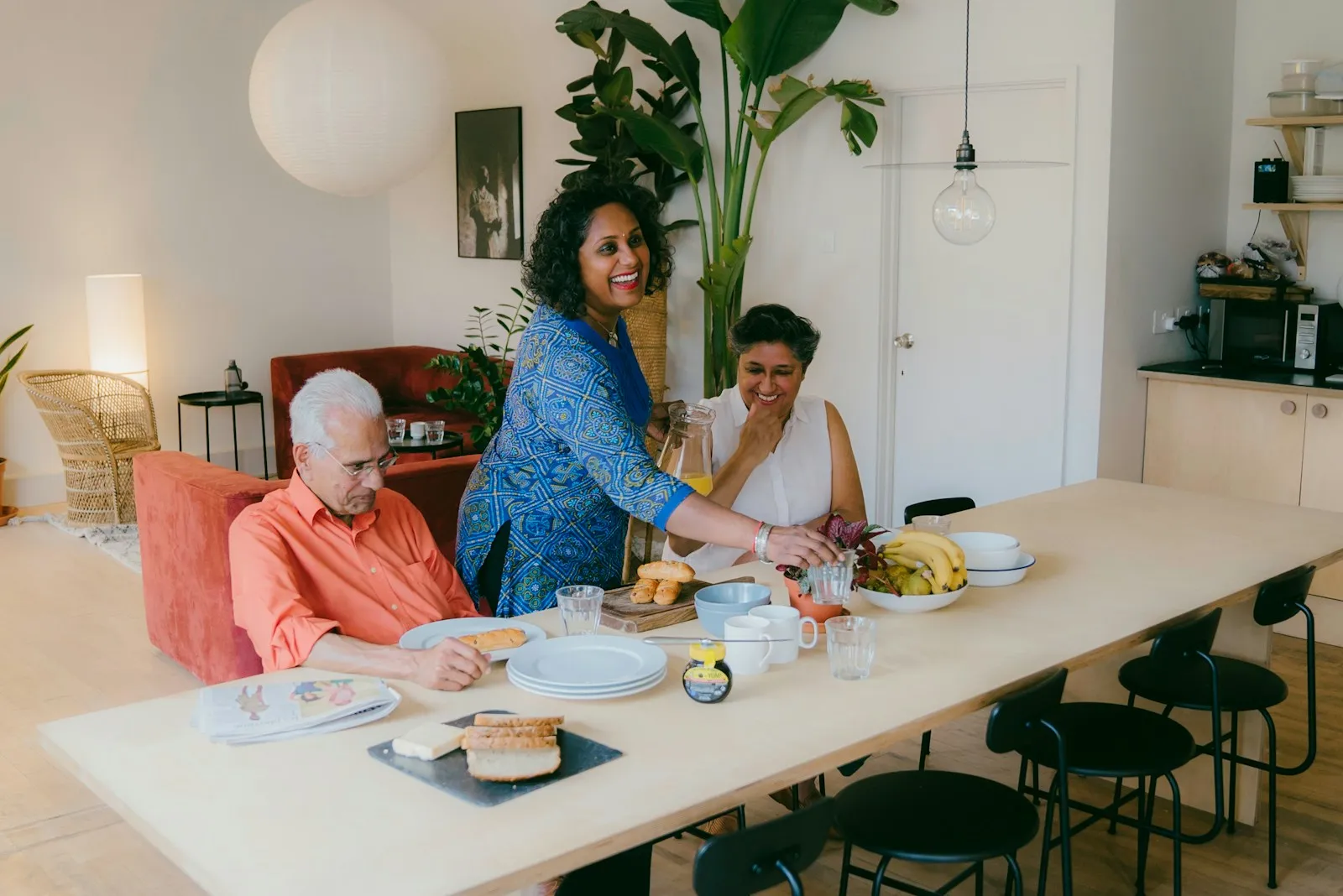 Several people sharing a meal at a long table in a bright communal room.